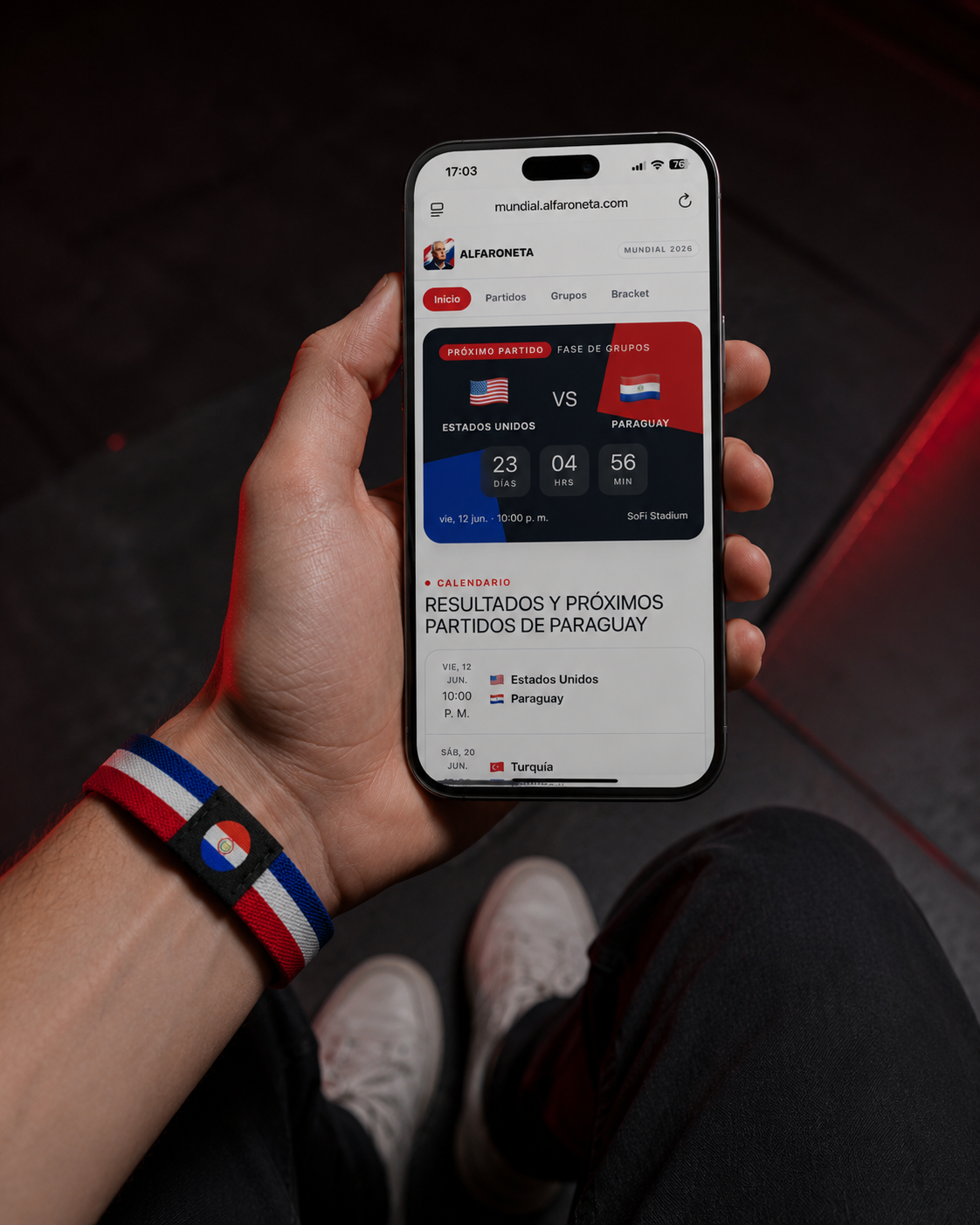 Hincha con la pulsera Alfaroneta usando el celular